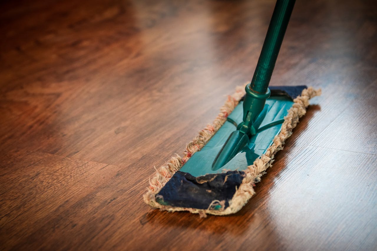 mobile-02 A detailed view of a mop cleaning a wooden floor, showing texture and pattern.